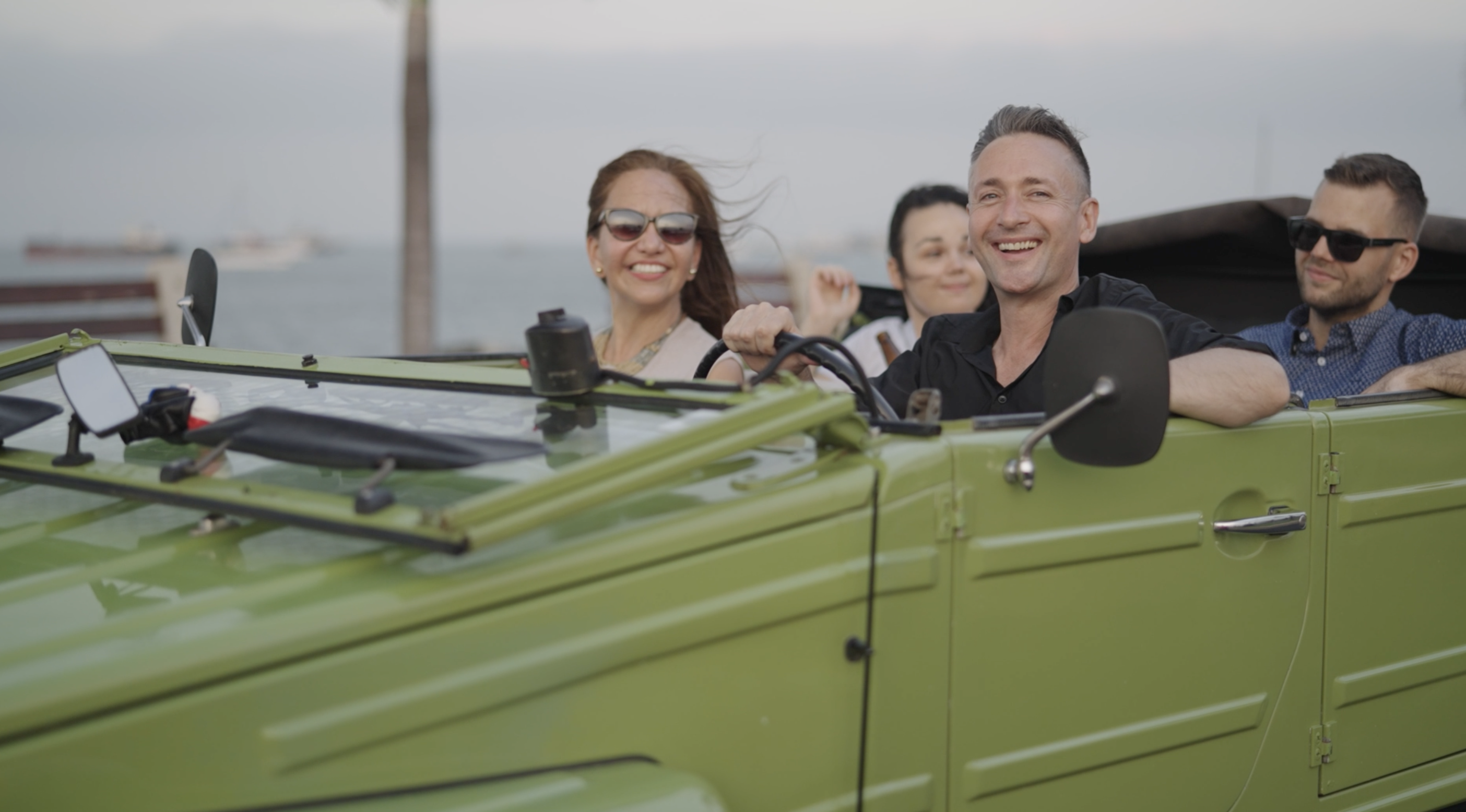 A classic VW Safari car driving through Panama City with the ocean in the background